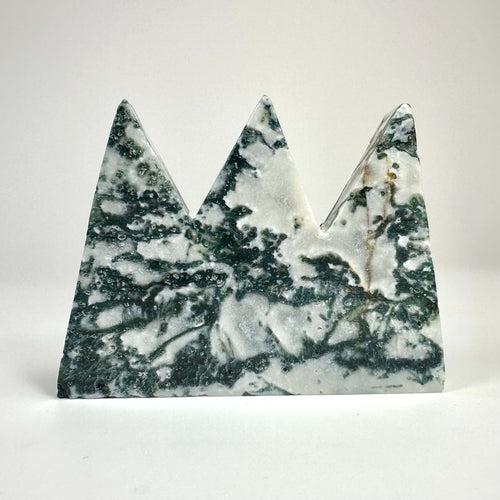 Mos agat bjergformet skulptur med grønne og hvide mønstre mod en lys baggrund.