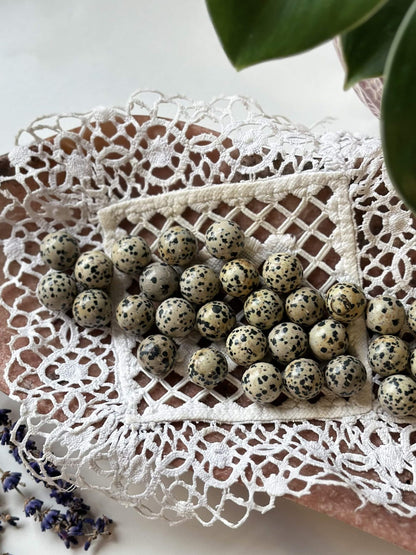 Dalmatiner mini kugler på hæklet dug, omkranset af blomster, skaber et elegant og naturligt arrangement.