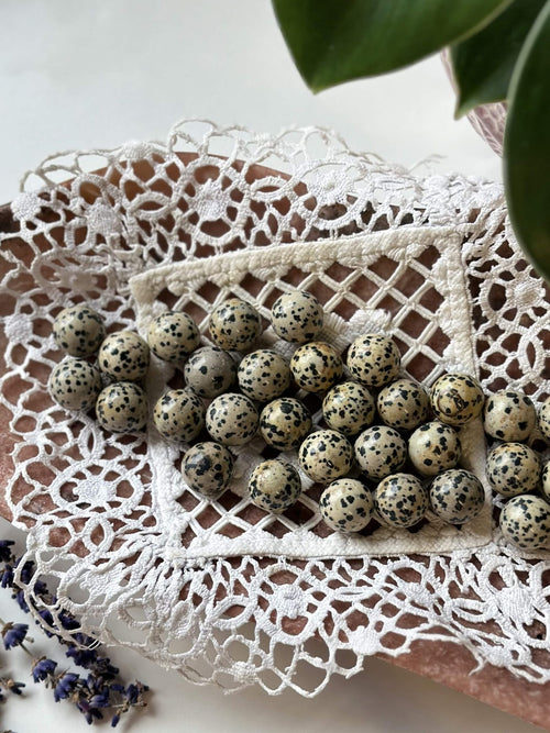 Dalmatiner mini kugler på hæklet dug, omkranset af blomster, skaber et elegant og naturligt arrangement.