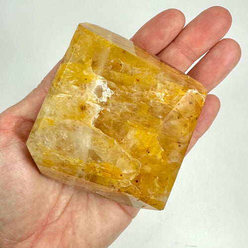 Hånd holder en Golden Healer krystal i fri form, gylden og gennemsigtig med naturlige mønstre.