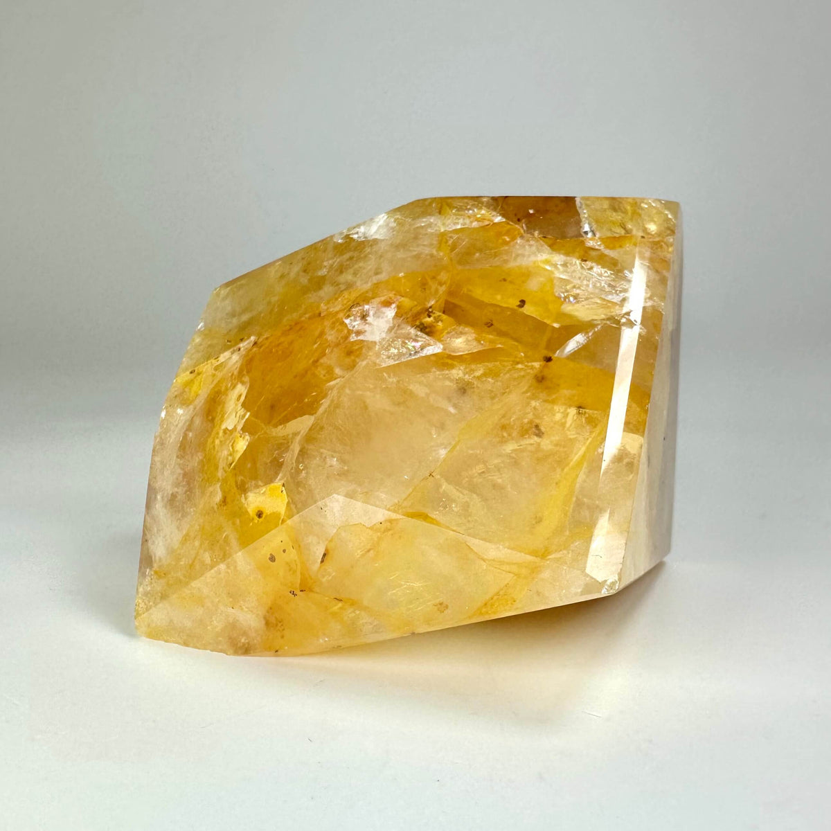 En stor, gul Golden Healer krystal med en glat overflade på en hvid baggrund.
