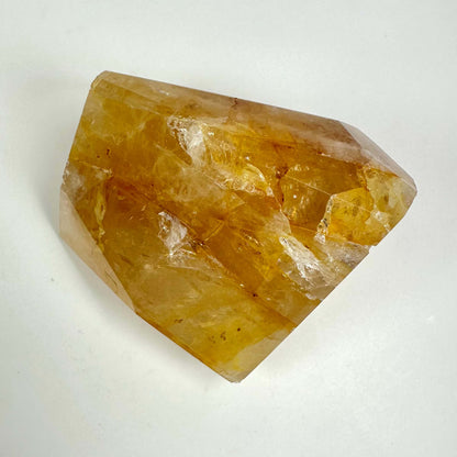 Golden healer krystal i fri form mod hvid baggrund, med gyldne nuancer og naturlige markeringer.