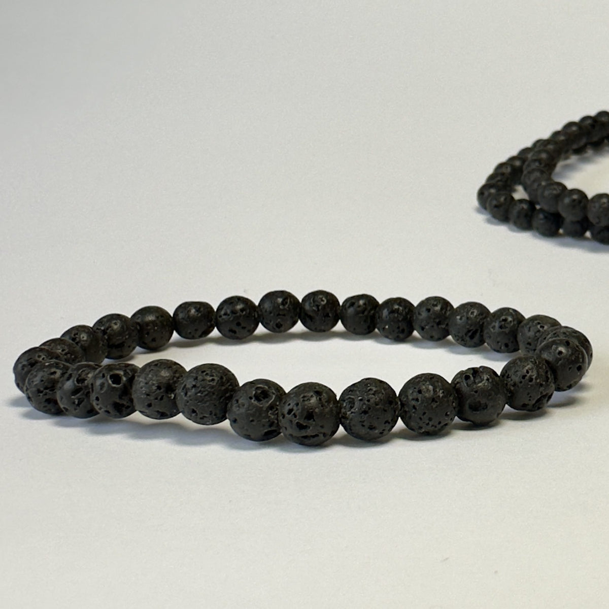 Sort lava armbånd med runde sten perler på en lys baggrund.