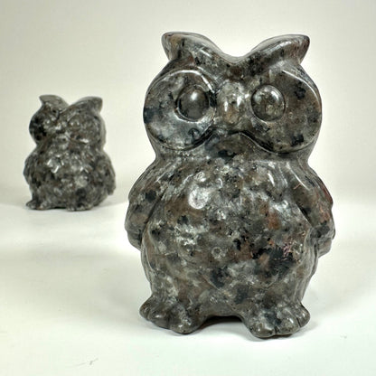 To Yooperlit ugler i sten på hvid baggrund; en tættere på, en i baggrunden.