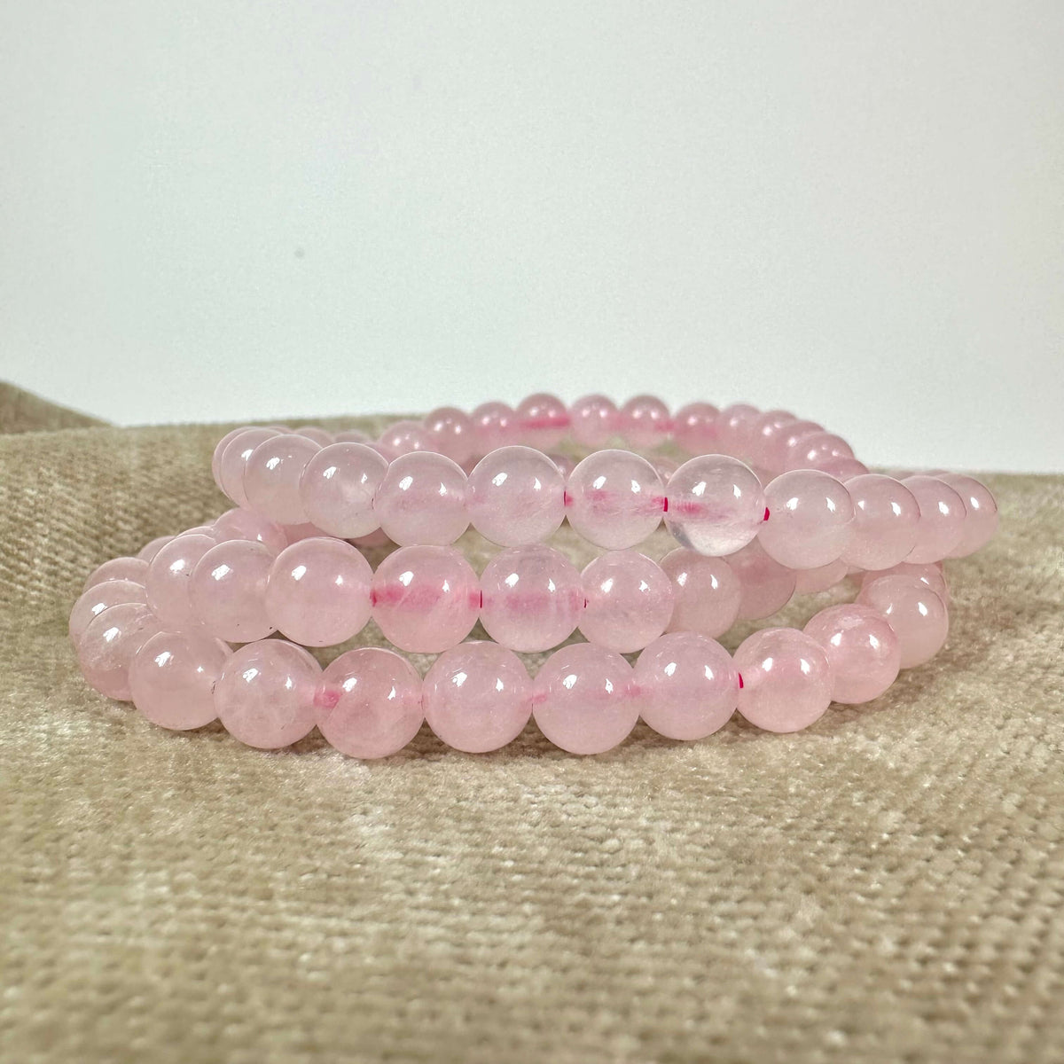 Et armbånd lavet af lyserøde perler på en lys baggrund.