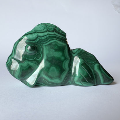 Malakit slørhale skulptur med smukke, grønne mønstre på en lys baggrund.