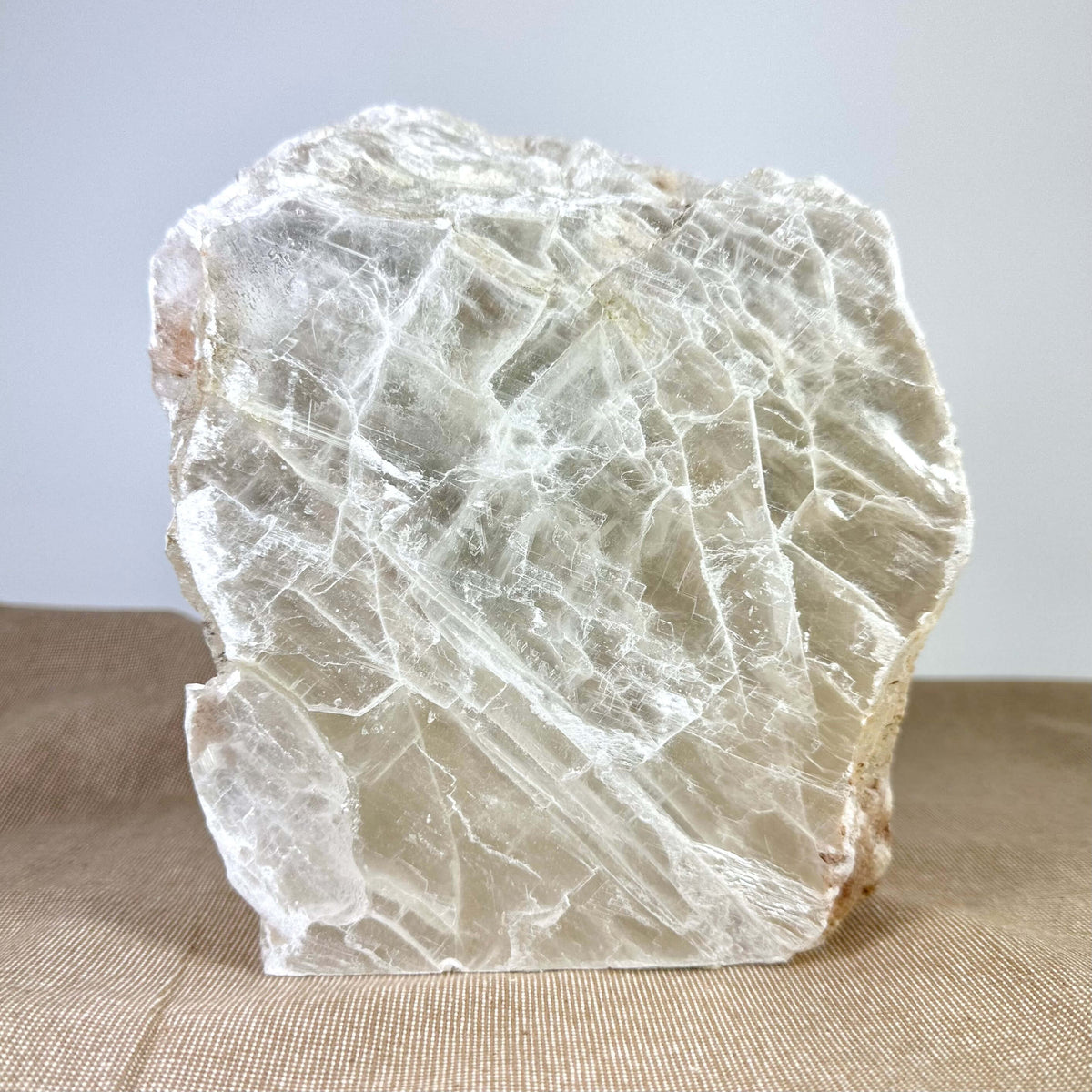 Håndskåret Mexicansk selenit lampe nr. 38 fremstår i naturlige, rå former med gennemsigtige lag og en krystalstruktur, der reflekterer lyset smukt. Lampen står på en neutral baggrund og udstråler ro og elegance, ideel til meditation, indretning og energirensning. Den bringer positiv energi ind i rummet og skaber en beroligende atmosfære med sit varme, dæmpbare lys.