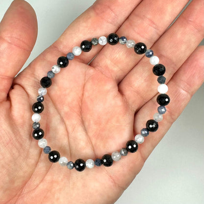 Armbånd med sorte, hvide og blå perler vises i håndfladen.