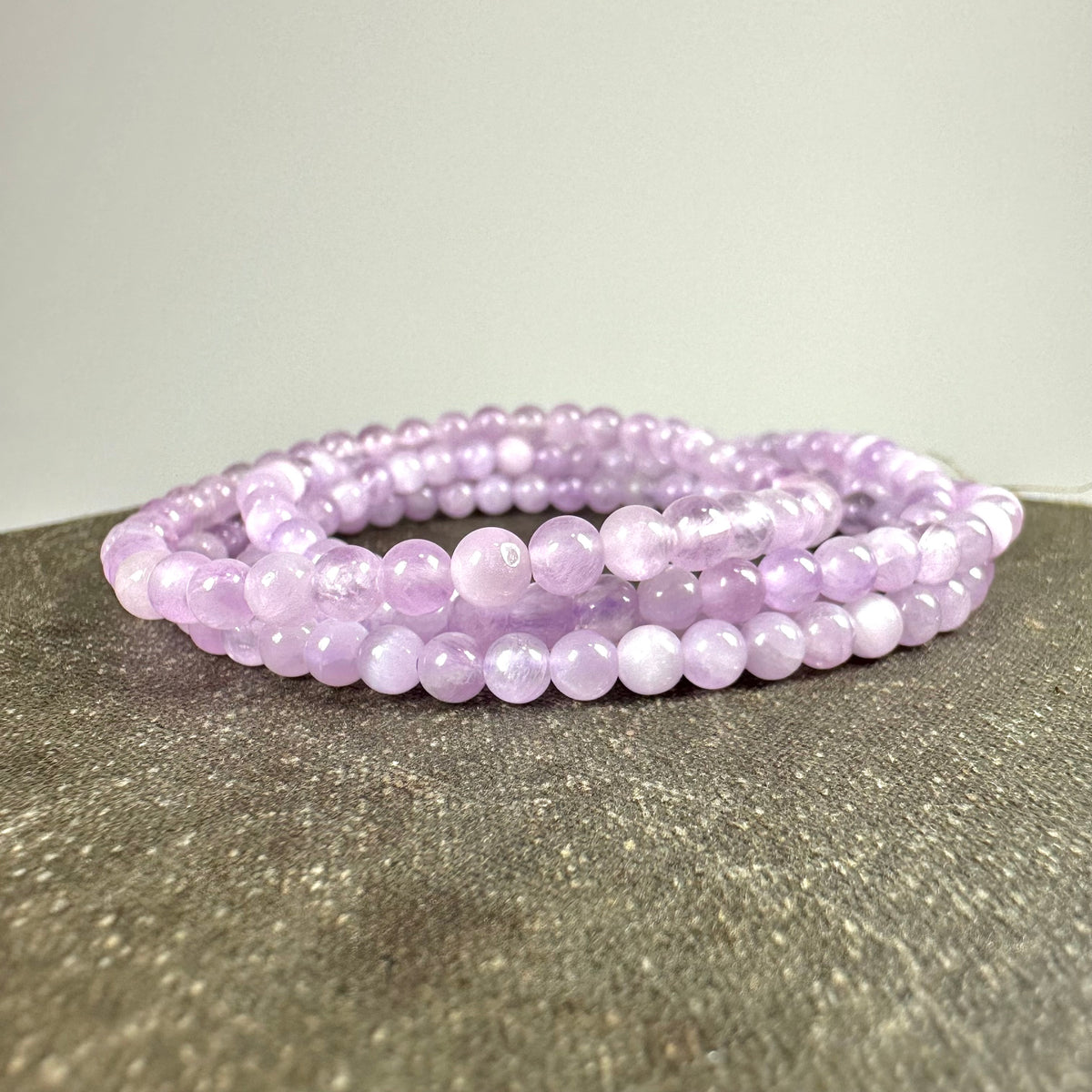 Ametyst armbånd med runde perler i lys lilla farve ligger på et bord.