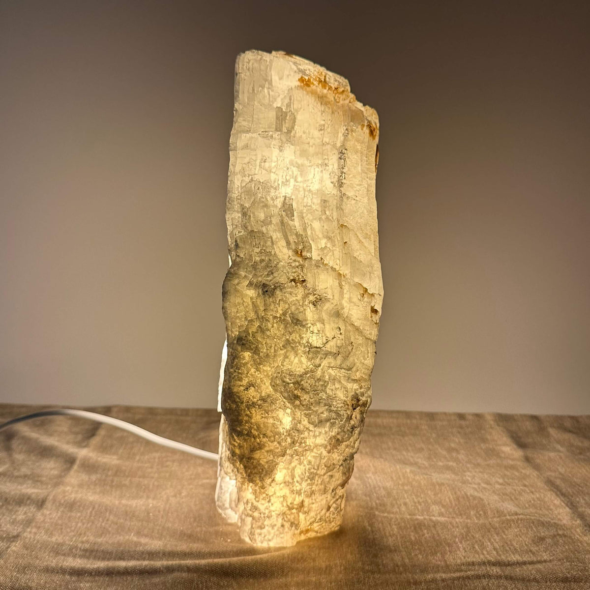 Billede af en oplyst mineralstenlampe på et bord mod en neutral baggrund.
