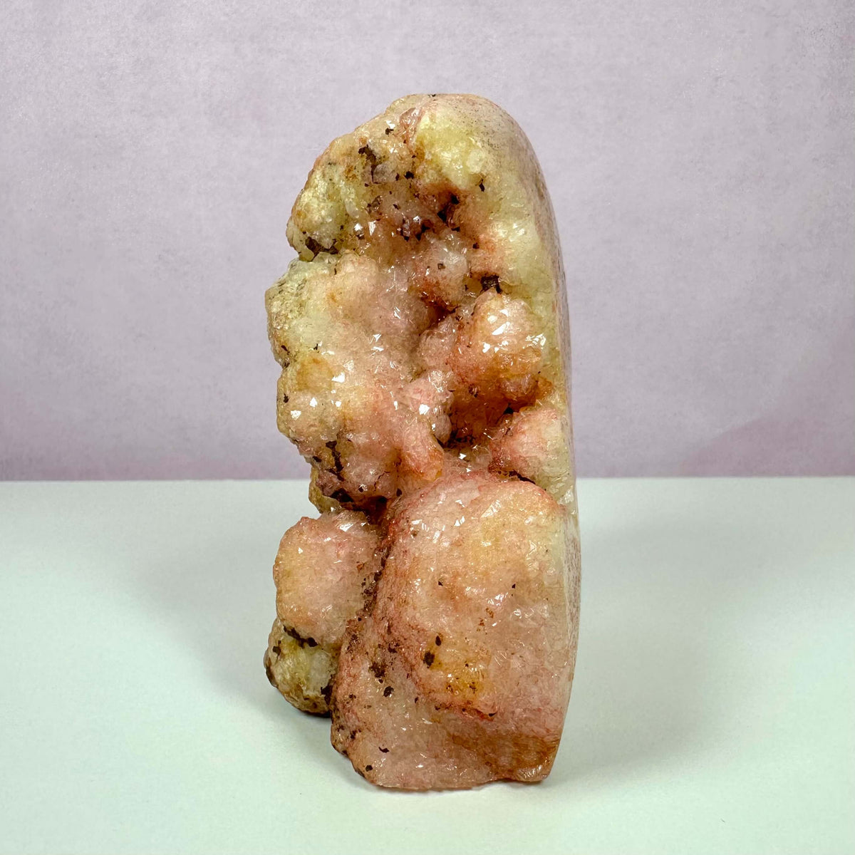 Pink Ametyst, unika – en sjælden og smuk krystal i bløde rosa og ferskenfarvede nuancer med naturlige glitrende overflader. Den markante struktur fremhæver dens unikke, krystallinske formation, som stammer fra geologiske forhold i Argentina og Brasilien. Krystallen er kendt for sine healende egenskaber, og siges at fremme kærlighed, følelsesmæssig balance og spirituel vækst gennem aktivering af hjertchakraet.
