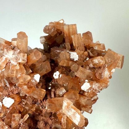 Aragonit klynge nr 4 er en smuk, brunlig-orange krystalformation med tydelige, prismeformede strukturer. Klyngen har en glansfuld overflade og består af tætliggende krystaller i forskellige størrelser. Den symboliserer jordforbindelse og balance og bruges ofte i meditation og energiarbejde. Perfekt som både dekorativ krystal og spirituelt værktøj til at styrke rodchakraet og skabe indre ro.