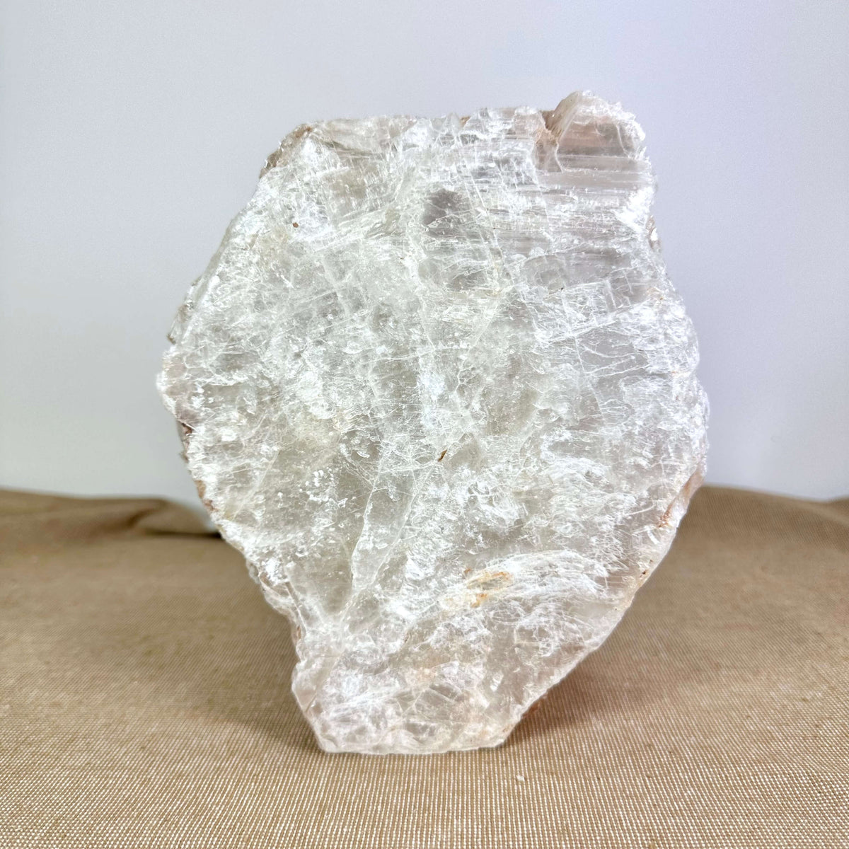 Mexicansk Selenit lampe nr 10 vist mod en neutral baggrund. Den håndskårne lampe består af rå, lagdelt selenitkrystal med et naturligt hvidt og gennemsigtigt udtryk. Dens organiske form og struktur fremhæver mineralets unikke karakter, som reflekterer lyset smukt. Lampen skaber en beroligende atmosfære og passer elegant ind i ethvert hjem. Ideel til meditation, afslapning og interiør.
