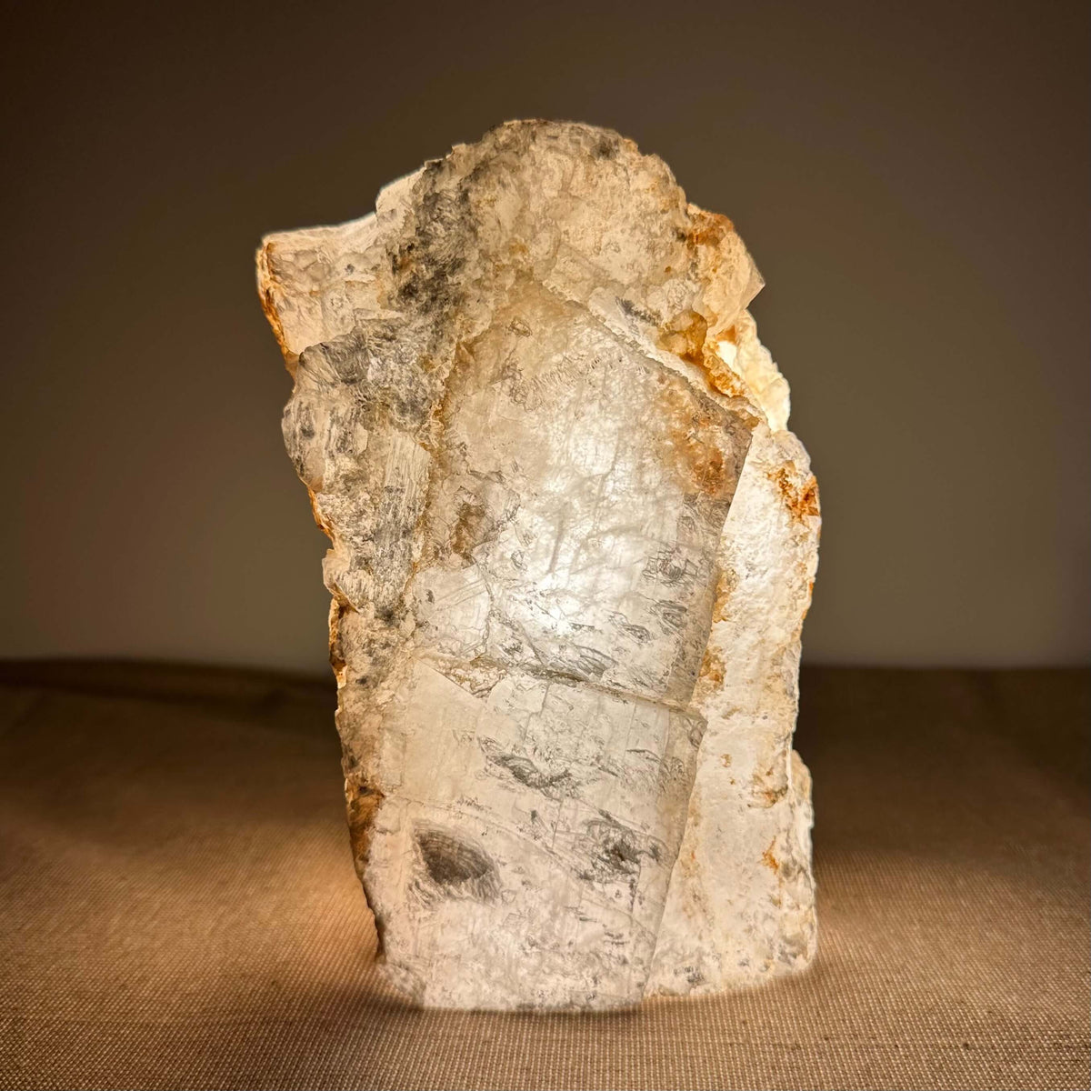 Mexicansk Selenit lampe nr. 33 lyser blidt op i varme, gyldne nuancer og fremviser sine naturlige, lagdelte krystalmønstre. Den håndskårne lampe udstråler ro og er ideel til meditation og indre balance. Selenitens silkebløde overflade og organiske form giver et æstetisk og spirituelt løft til enhver indretning og skaber en harmonisk atmosfære i rummet.