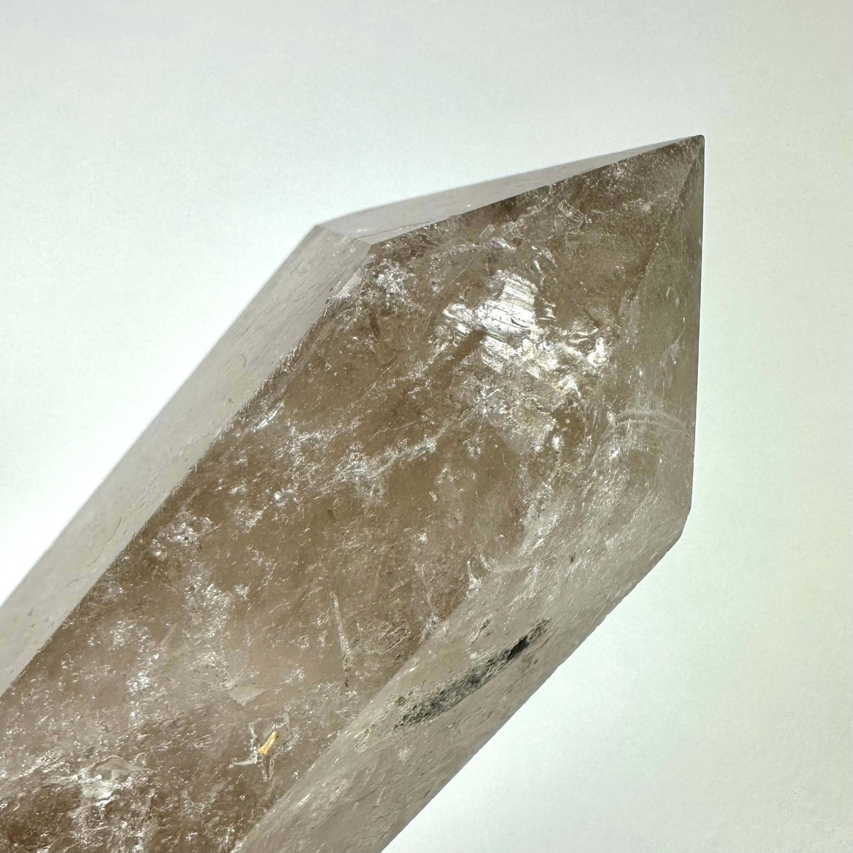 Billedet viser et røgkvarts tårn med en naturlig brunlig nuance og polerede flader, der reflekterer lyset smukt. Krystallen er formet i en spids struktur, ideel til energiarbejde og meditation. Røgkvarts menes at beskytte mod negativitet og skabe jordforbindelse, og bruges ofte til at balancere rod- og kronechakraet. Et kraftfuldt redskab i både spirituelle og dekorative sammenhænge.