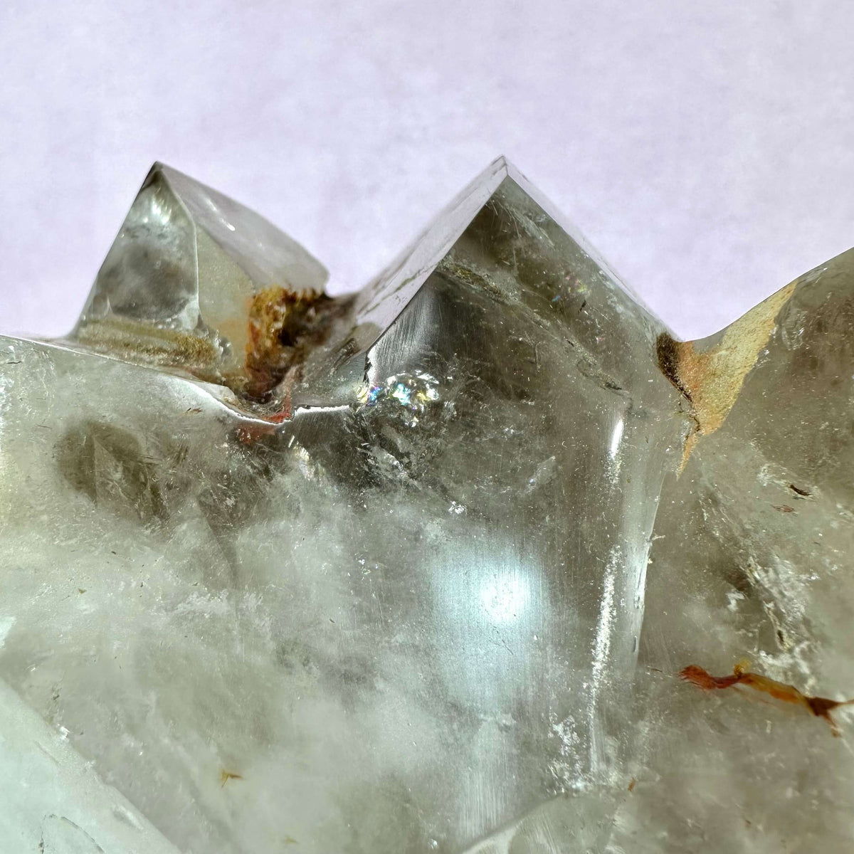 Nærbillede af en Røgkvarts klynge XXL med tydelige, naturlige krystalformationer i brunlige og grålige nuancer. Krystallens overflade fremstår rå og ubehandlet med synlige mineralforekomster og lyse reflekterende flader. Den kraftfulde sten forbindes med spirituel beskyttelse, rensning af negativ energi og styrkelse af jordforbindelse via rodchakraet. Ideel til både dekoration og meditation.