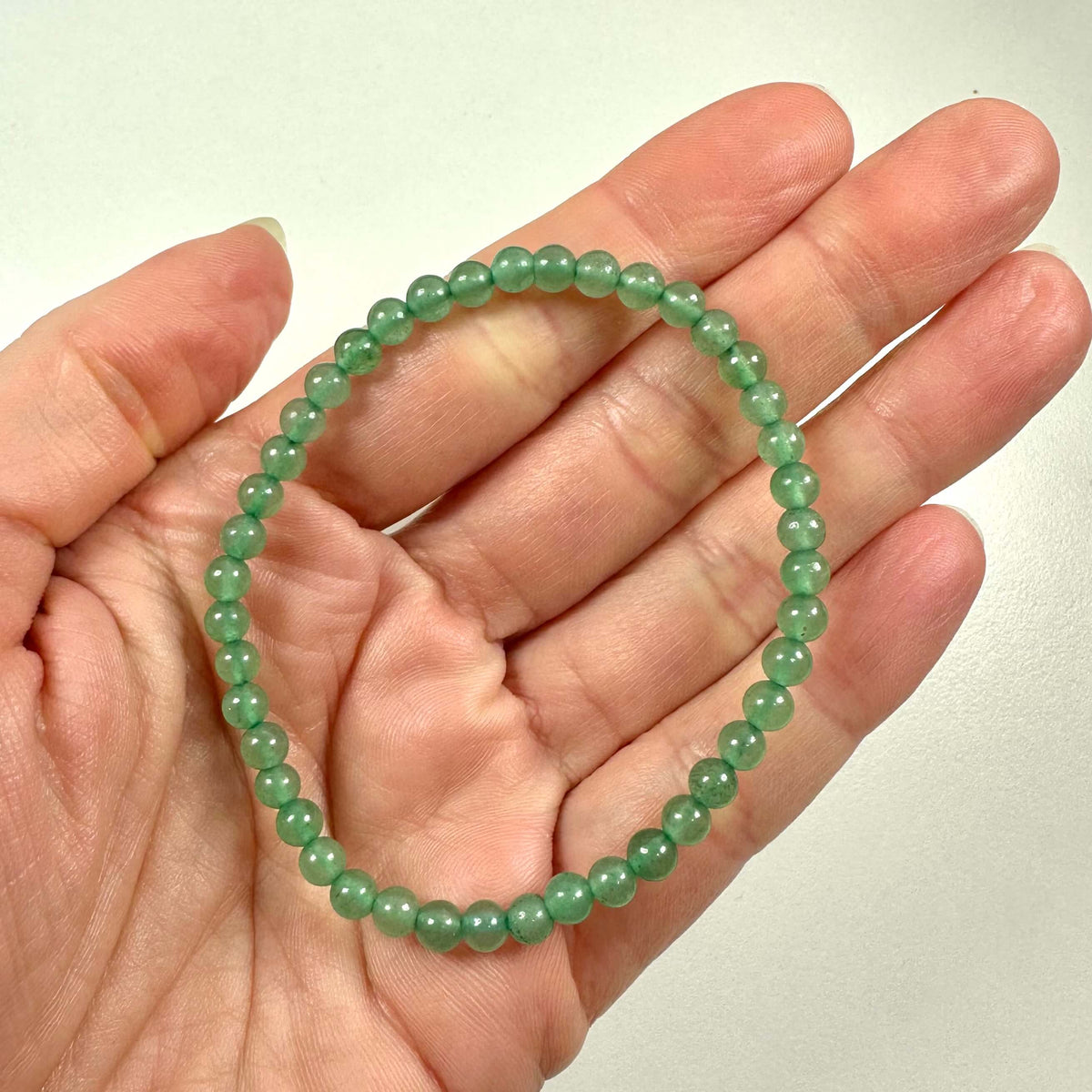 Grønt aventurin armbånd med små polerede perler i en åben håndflade