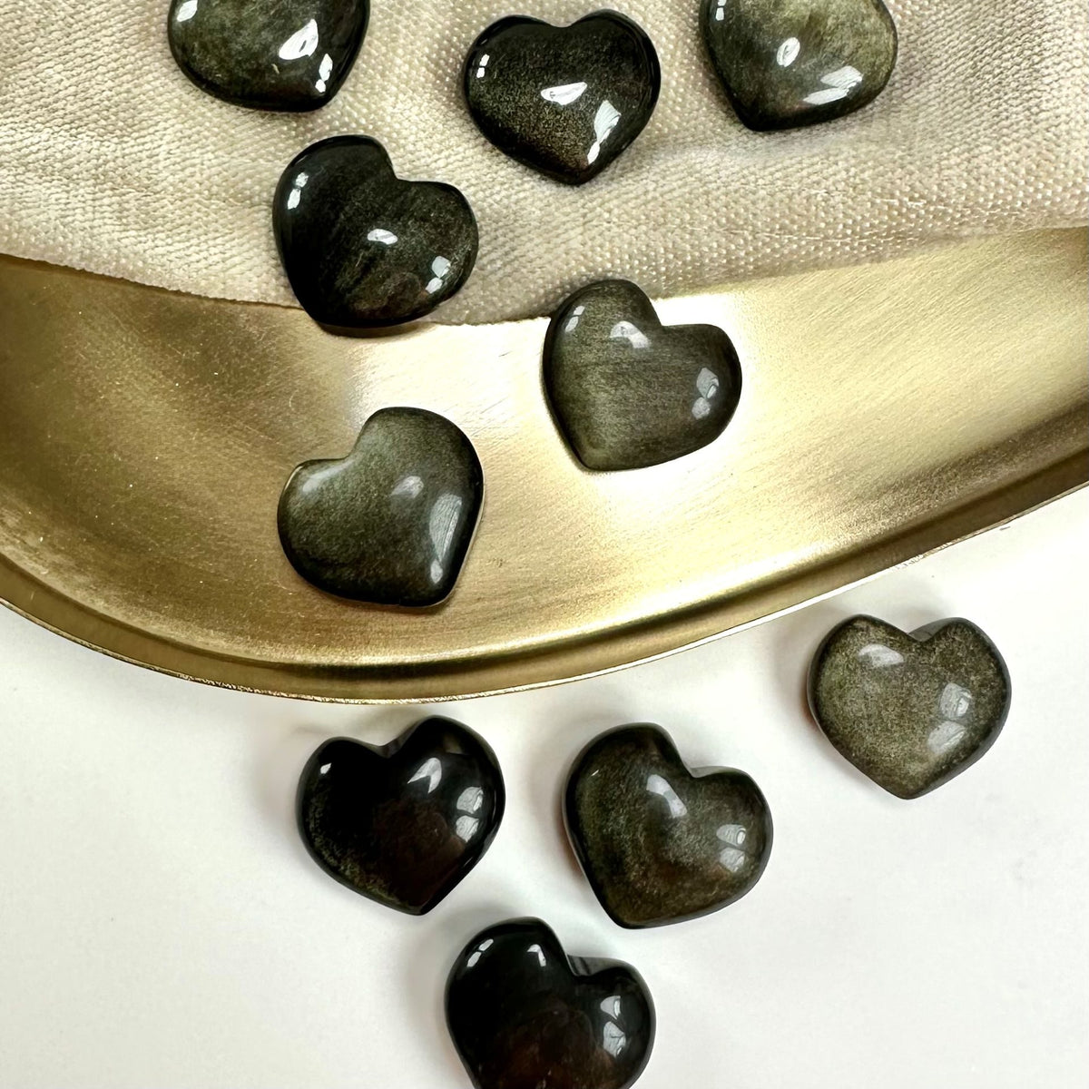 Guld Obsidian hjerter spredt på en gylden bakke med lys underlag.