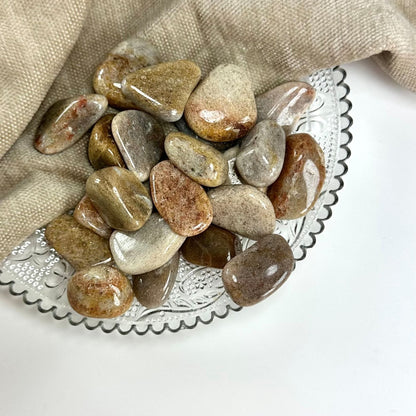 Glatte Kvartsit karamelsten ligger på en dekoreret glasskål ved siden af en beige klud.
