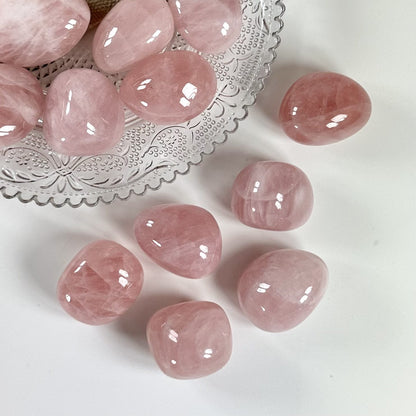 Rosenkvarts lommesten med bånd i lys pink på en dekoreret glasskål og bord.