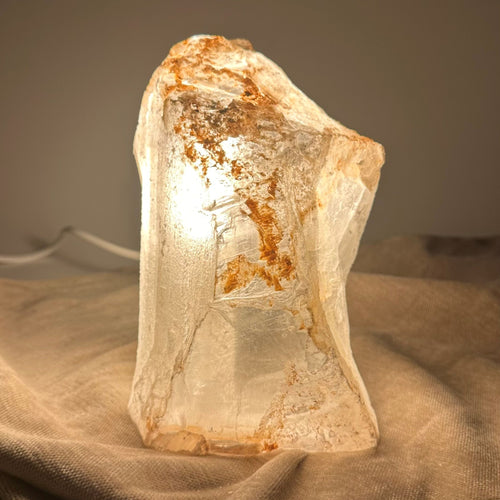 Mexicansk Selenit lampe nr 22 lyser med et varmt skær, placeret på en lys klædeoverflade.