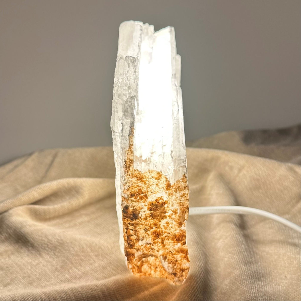 Mexicansk Selenit lampe nr 23 lyser op, placeret på en beige klud med en tilsluttet ledning.