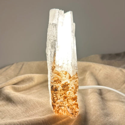 Mexicansk Selenit lampe nr 23 lyser op, placeret på en beige klud med en tilsluttet ledning.