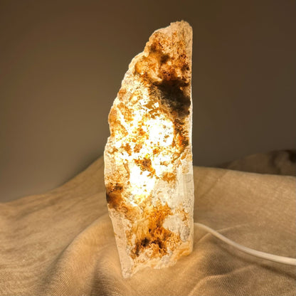 Mexicansk Selenit lampe nr 47 lyser med varmt skær, placeret på en beige stofoverflade.