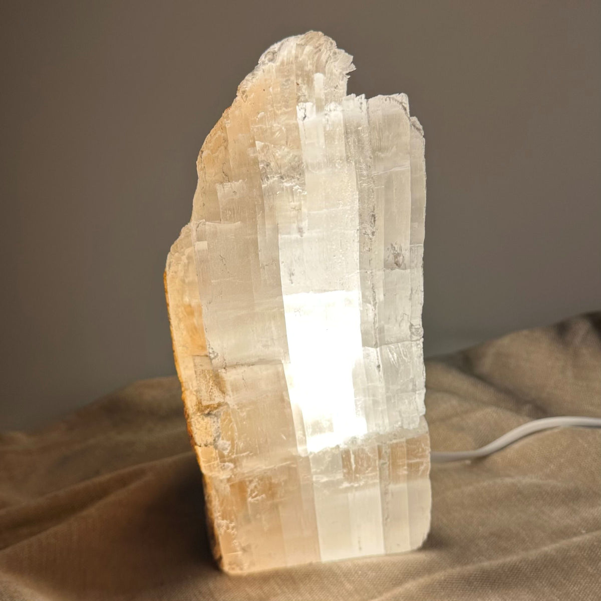 Mexicansk Selenit lampe nr 49 lyser op med en varm glød på et neutralt underlag.