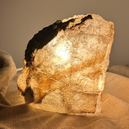 Mexicansk Selenit lampe nr 4 lyser varmt op i et dæmpet rum, omgivet af en blød stofbaggrund.