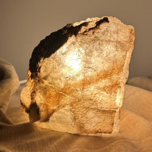 Mexicansk Selenit lampe nr 4 lyser varmt op i et dæmpet rum, omgivet af en blød stofbaggrund.
