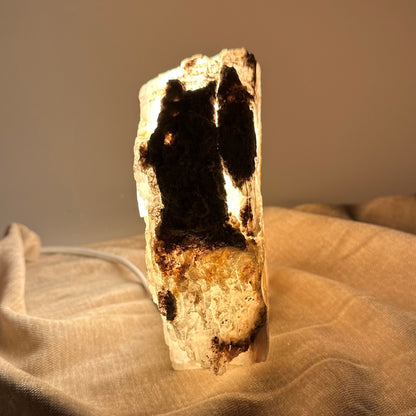 Mexicansk Selenit lampe nr 4 lyser op i en varm glød, stående på et tekstureret stofunderlag.