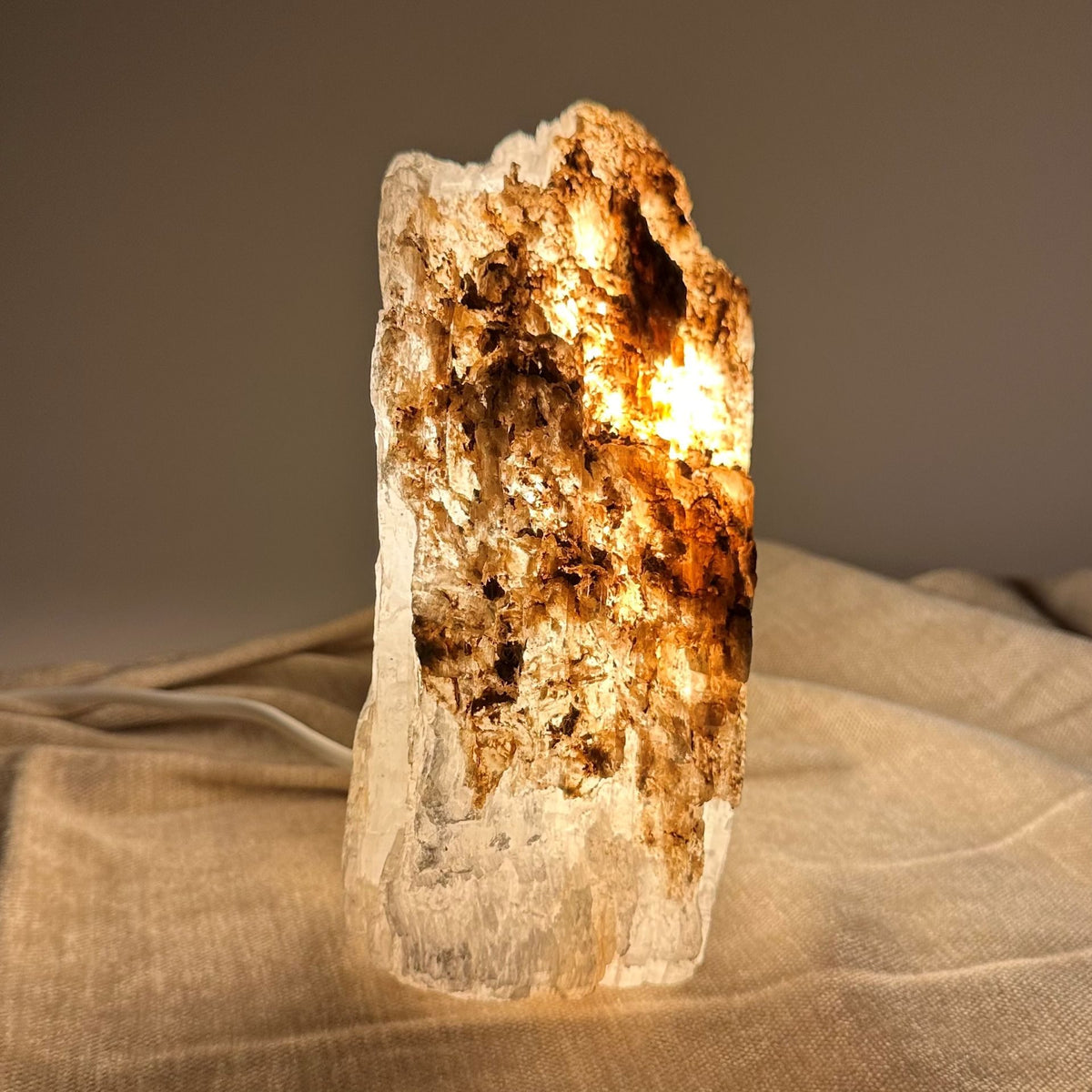 Mexicansk Selenit lampe nr 28 lyser op med varm glød på beige baggrund.