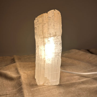 Mexicansk Selenit lampe nr 29 på en beige overflade, der lyser blødt med en varm glød.