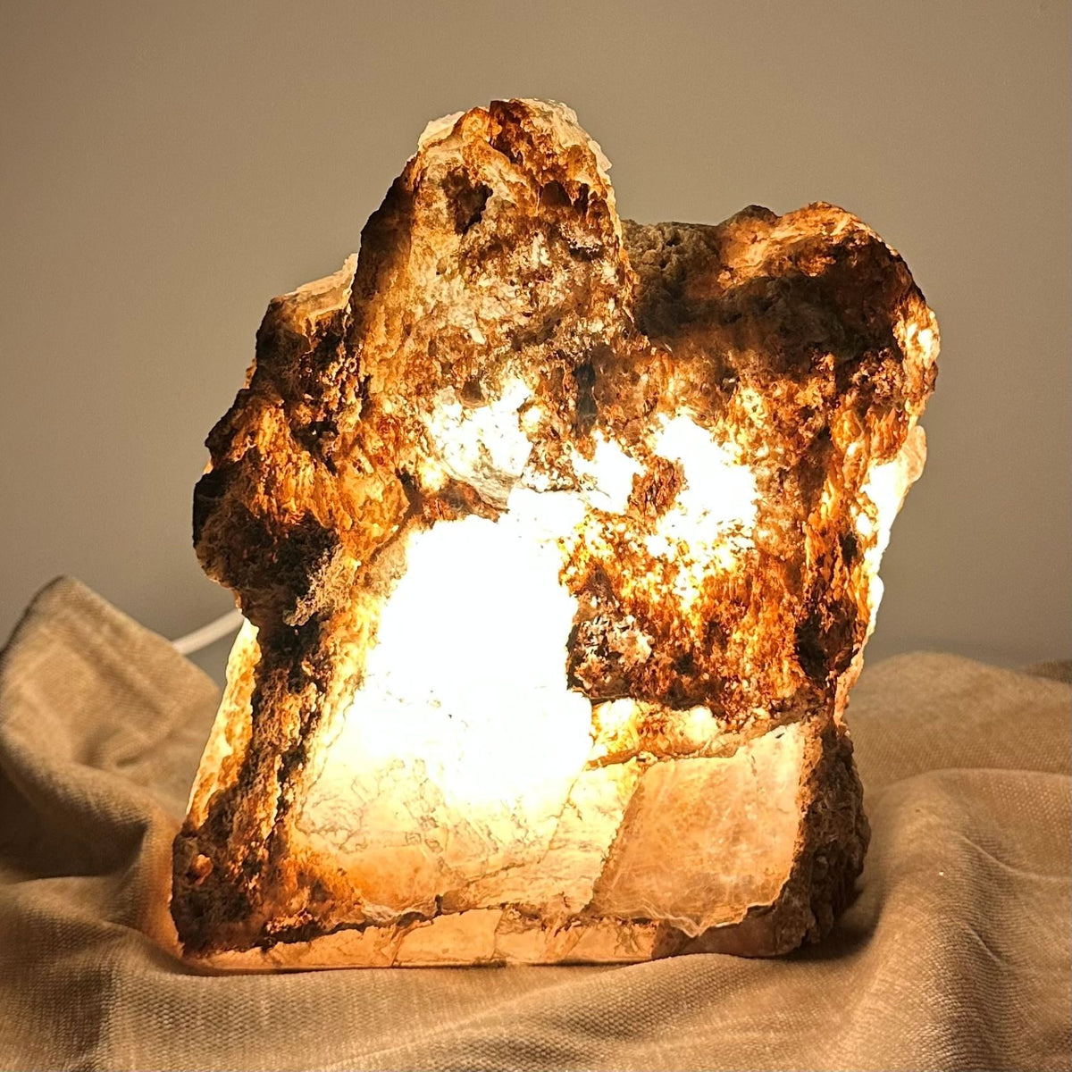 Mexicansk Selenit lampe nr 51, lyst op indefra, med en naturligt ujævn overflade på en beige klud.