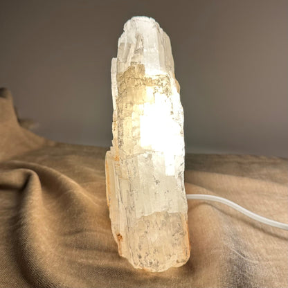Mexicansk Selenit lampe nr 1, oplyst og placeret på en beige overflade.