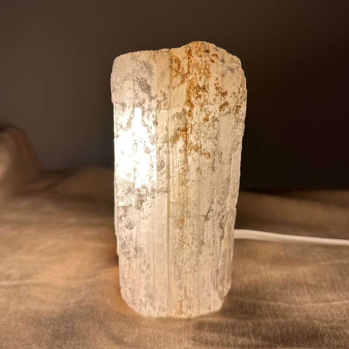 Mexicansk Selenit lampe nr 21 lyser op, med neutral baggrund og ledning synlig på en stofflade.