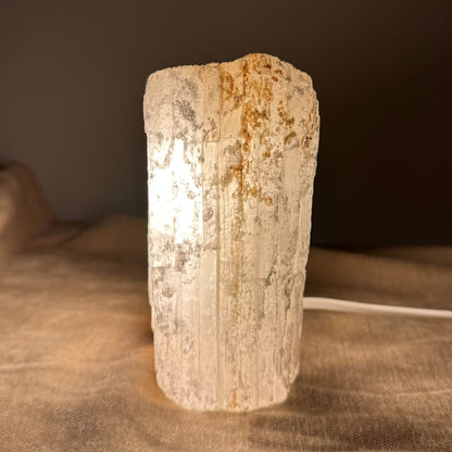 Mexicansk Selenit lampe nr 21 lyser op, med neutral baggrund og ledning synlig på en stofflade.