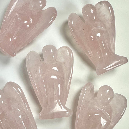 Fem små rosenkvarts engle ligger arrangeret på en hvid baggrund.