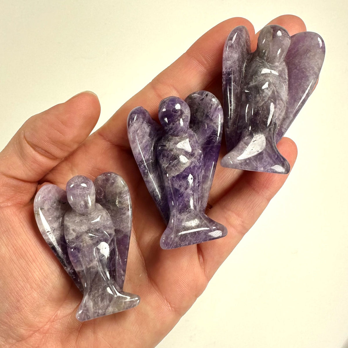 Hånd holder tre små amethyst englefigurer.