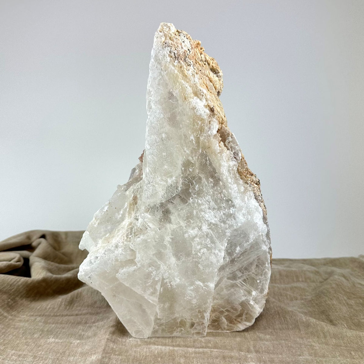 Mexicansk Selenit lampe nr 19 på en lys beige klud, en stor, ujævn krystal med naturlige mineraltoner.