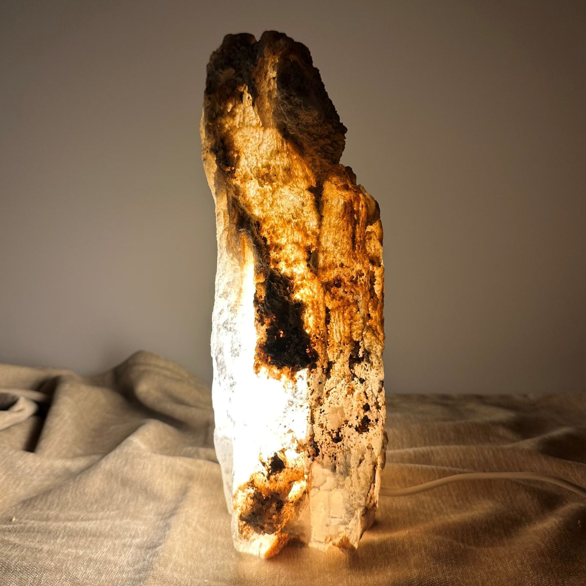 Mexicansk Selenit lampe nr 19 lyser op med varme nuancer på et neutralt bagtæppe.