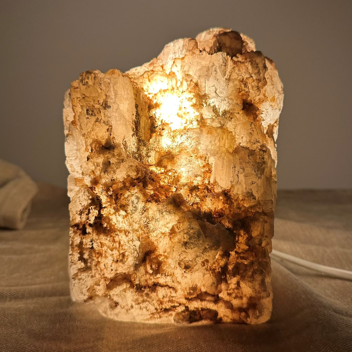 Mexicansk Selenit lampe nr 56 med varm belysning, står på en kludoverflade.