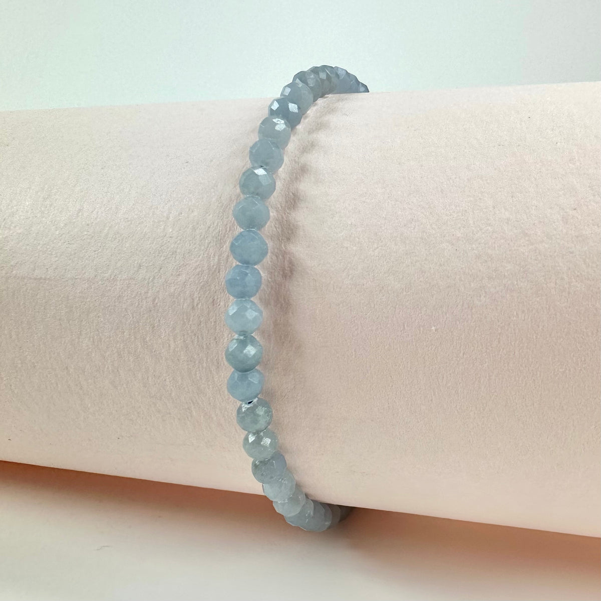 Angelit armbånd med lys blå facetterede perler på en hvid baggrund.