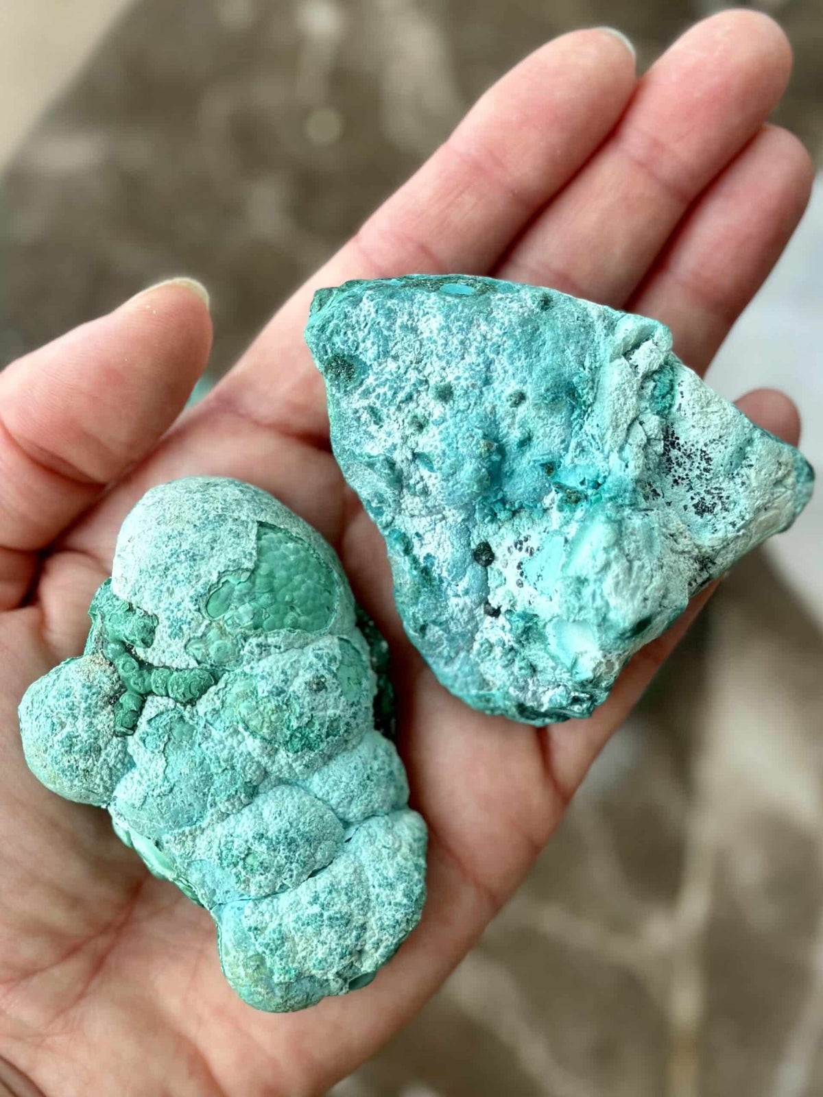To stykker Chrysocolla med Malakit, holdt i en hånd.