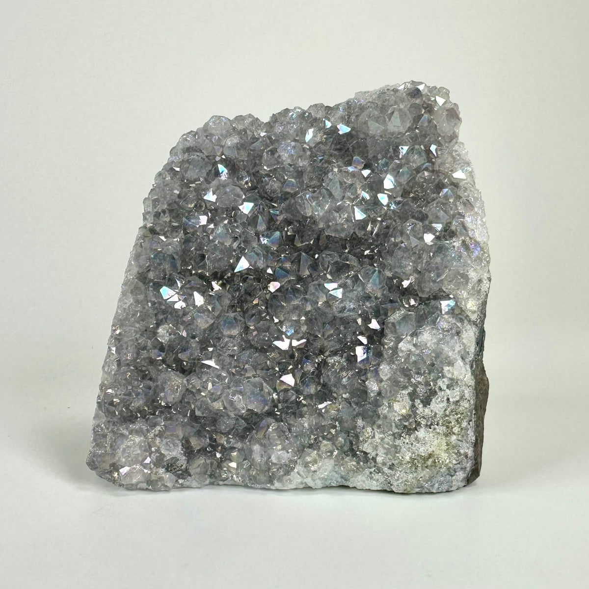 Ametyst aura geode med glitrende krystaller på en lys baggrund.