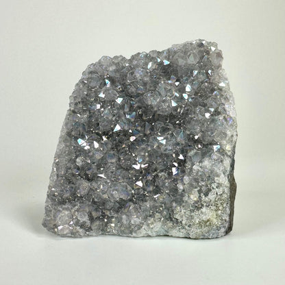 Ametyst aura geode med glitrende krystaller på en lys baggrund.