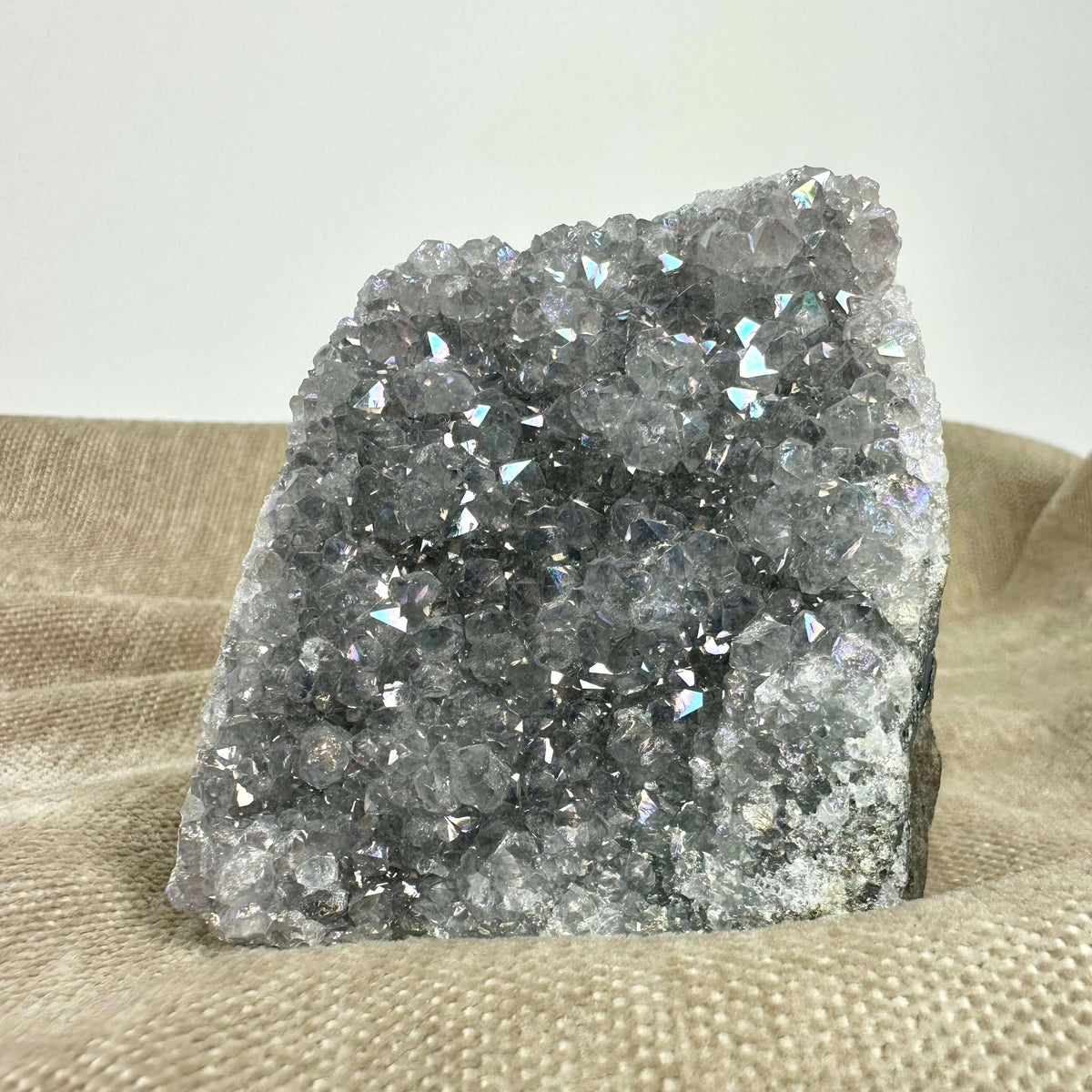 Ametyst aura geode med glitrende krystaller på en tekstureret baggrund.
