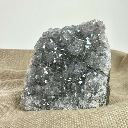 Ametyst aura geode med glitrende krystaller på en tekstureret baggrund.