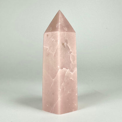 Pink opal tårn med glat, lys overflade mod en neutral baggrund.